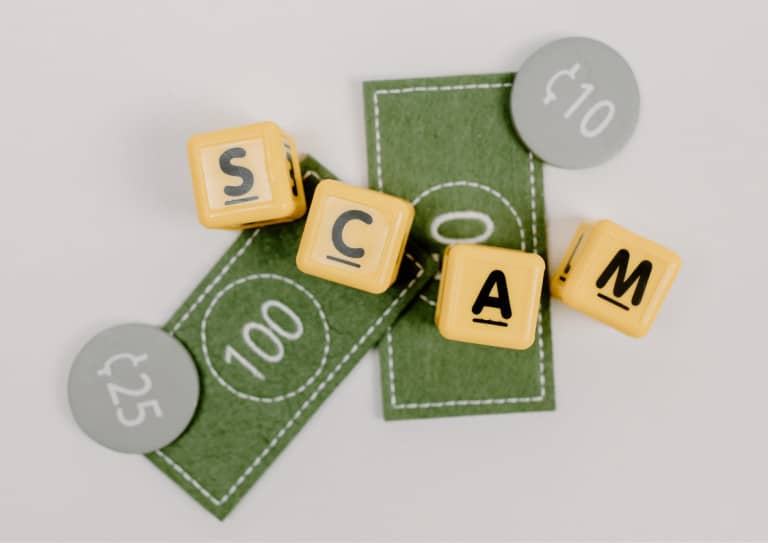 Scam spelled out using letterblocks on top of play money